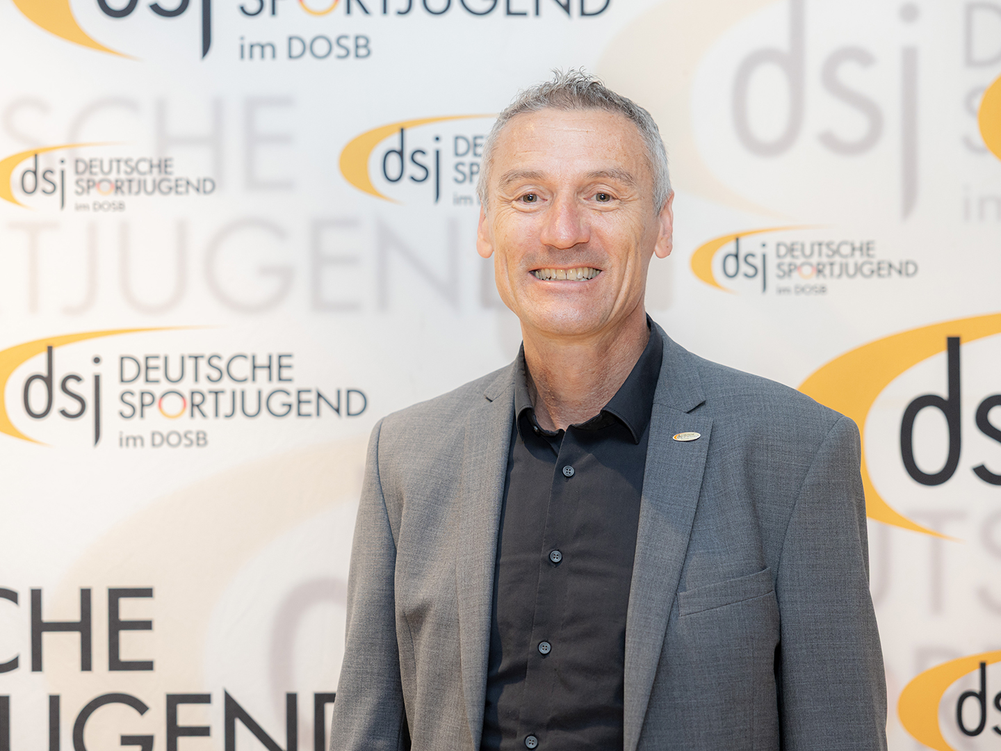 Porträt von Dominic Ullrich vor einer dsj-Logowand.