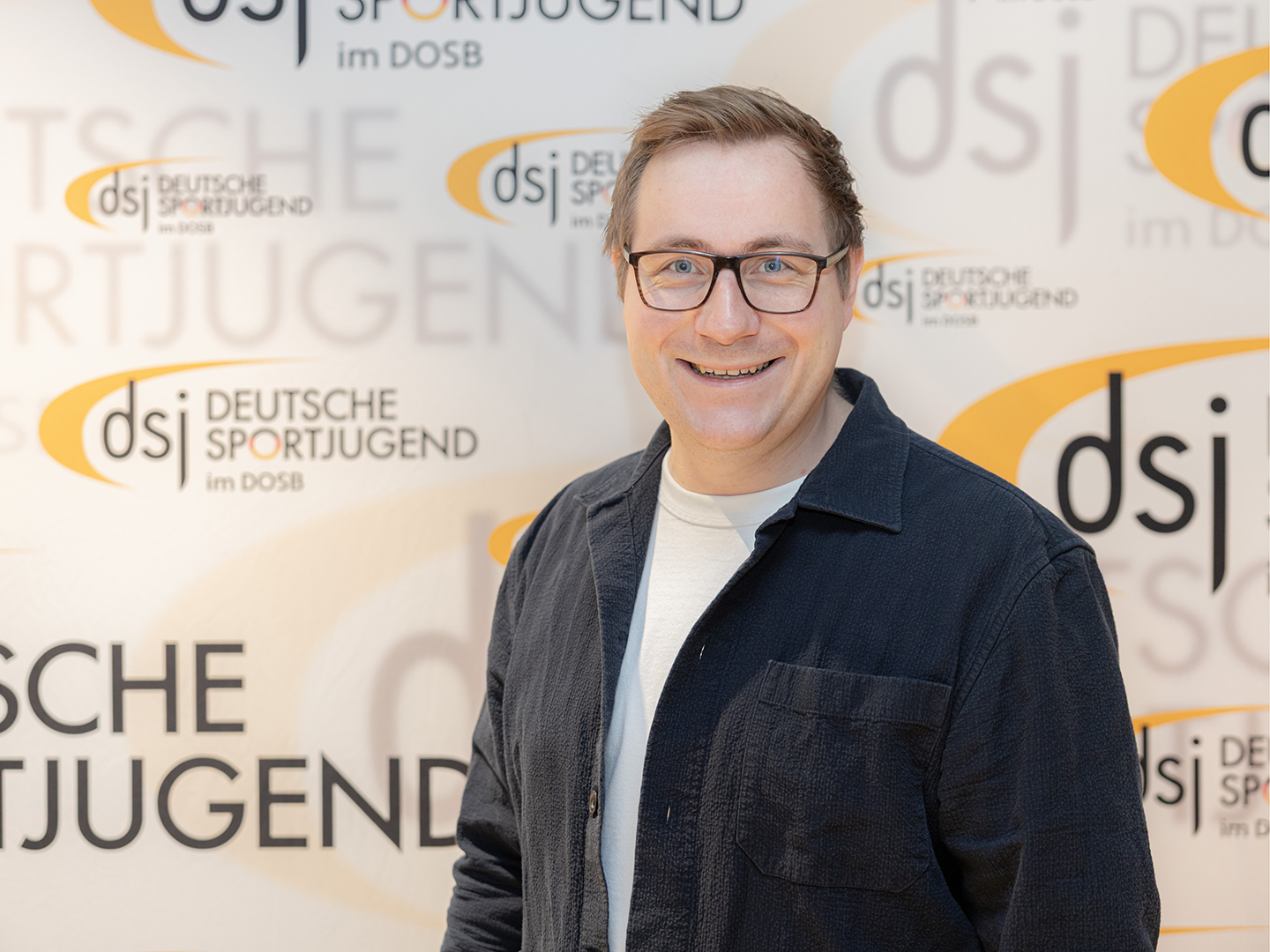 Porträt von Julian Lagemann vor einer dsj-Logowand.