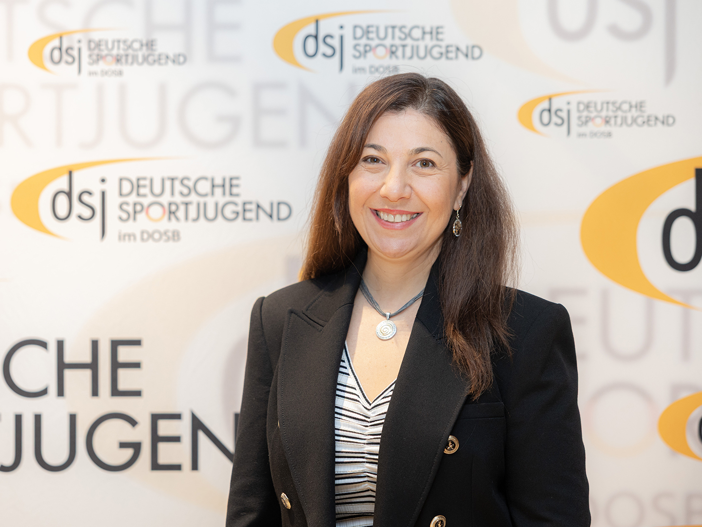Porträt von Keren Vogler vor einer dsj-Logowand.