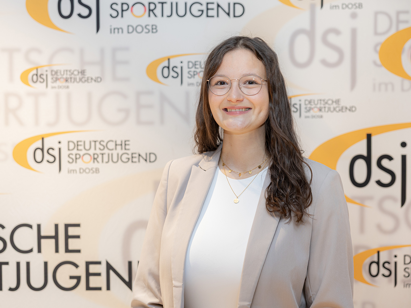 Porträt von Leandra Götz vor einer dsj-Logowand.