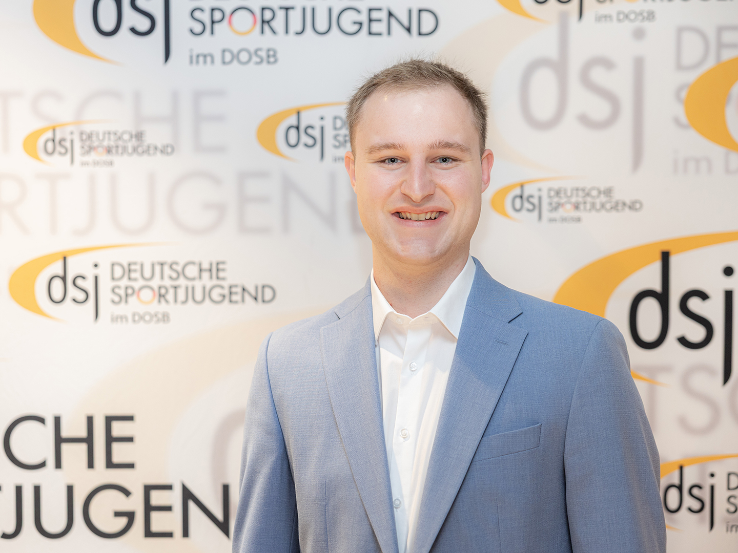 Porträt von Yannik Kiesel vor einer dsj-Logowand.