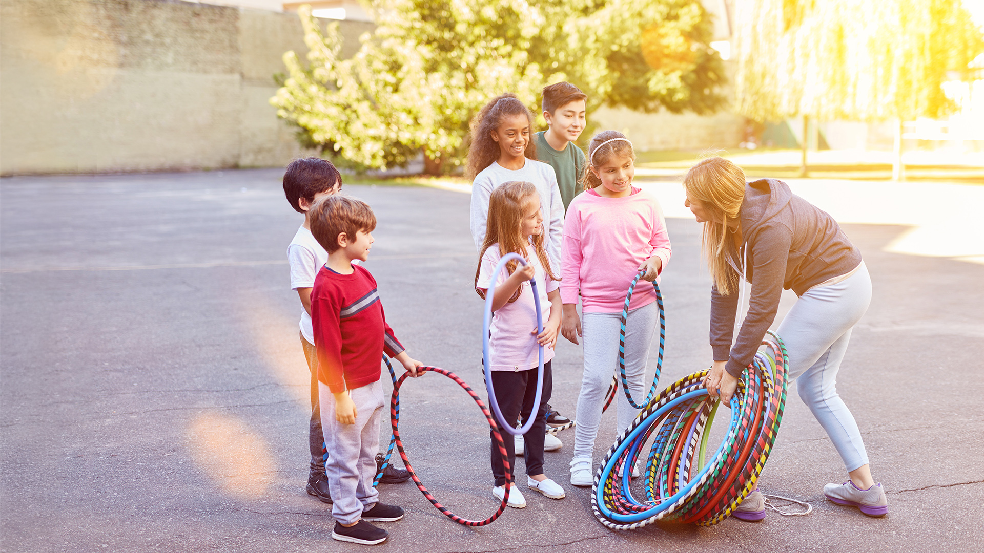 Gruppe von Kindern beim Bewegungstraining im Freien mit Sportreifen, angeleitet von einer Übungsleiterin. Die Szene zeigt aktive Gesundheitsförderung und frühe Bewegungsbildung im Rahmen der Initiative ‚Gemeinsam gegen Adipositas‘, unterstützt durch die Deutsche Sportjugend und die Leopoldina.