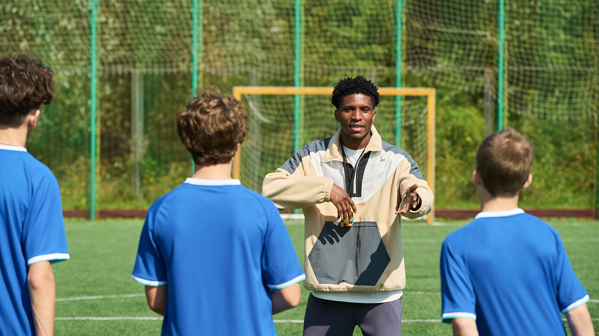 Trainer gibt Anweisungen an Jugendliche in einem Sportverein.