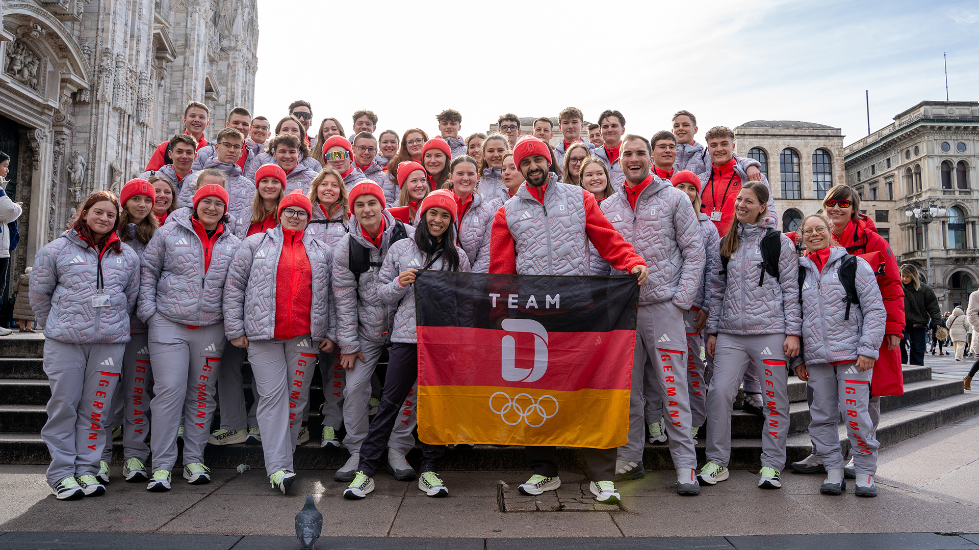 Teilnehmende des Deutschen Olympischen Jugendlagers vor dem Mailänder Dom gemeinsam mit dem Eistanzpaar Jennifer Janse van Rensburg und Benjamin Steffan.