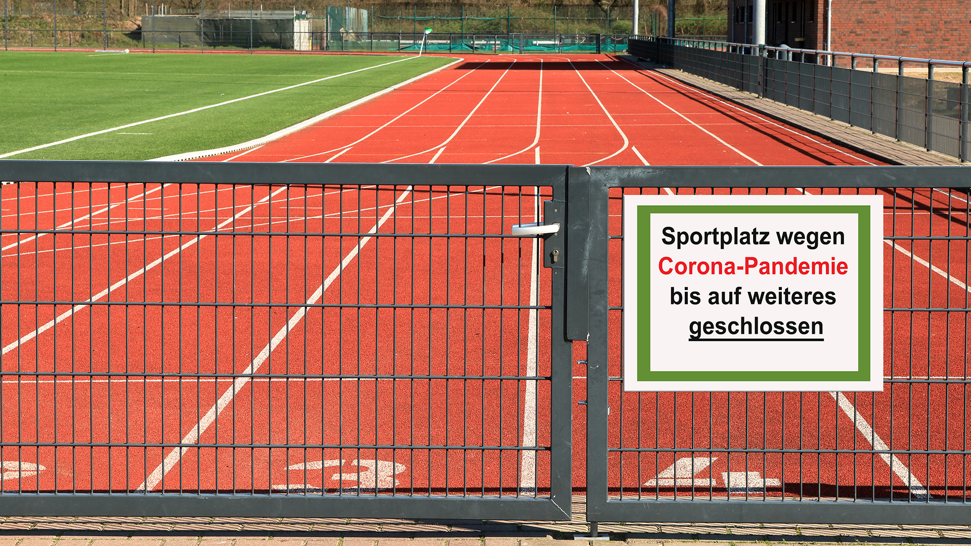 Verschlossener Sportplatz mit Laufbahn und Hinweisschild zur Schließung aufgrund der Corona‑Pandemie, das die Einschränkungen für Sport, Bewegung und Teilhabe verdeutlicht.