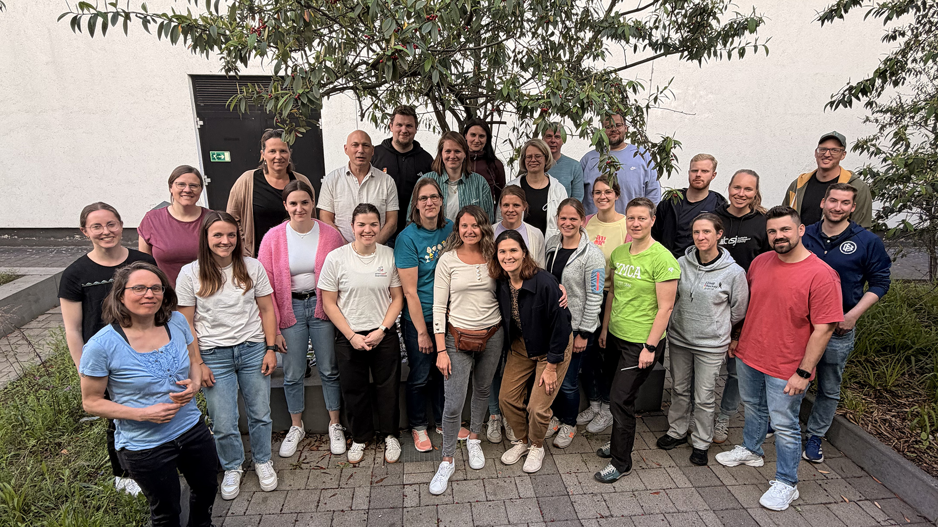 Teilnehmende der dsj- und DOSB-Tagung „Zukunft des Jugendsports in der DOSB-Ausbildungsreform neu denken“ stehen für ein Gruppenfoto im Außenbereich.