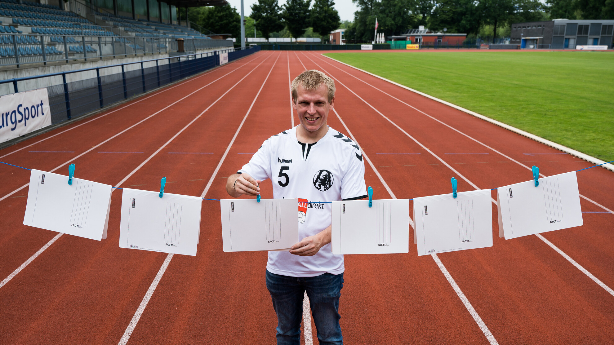 Symbolische Darstellung von Bürokratie im Sport mit einem Sportler, der Dokumente an einer Wäscheleine aufhängt. Stadion im Hintergrund