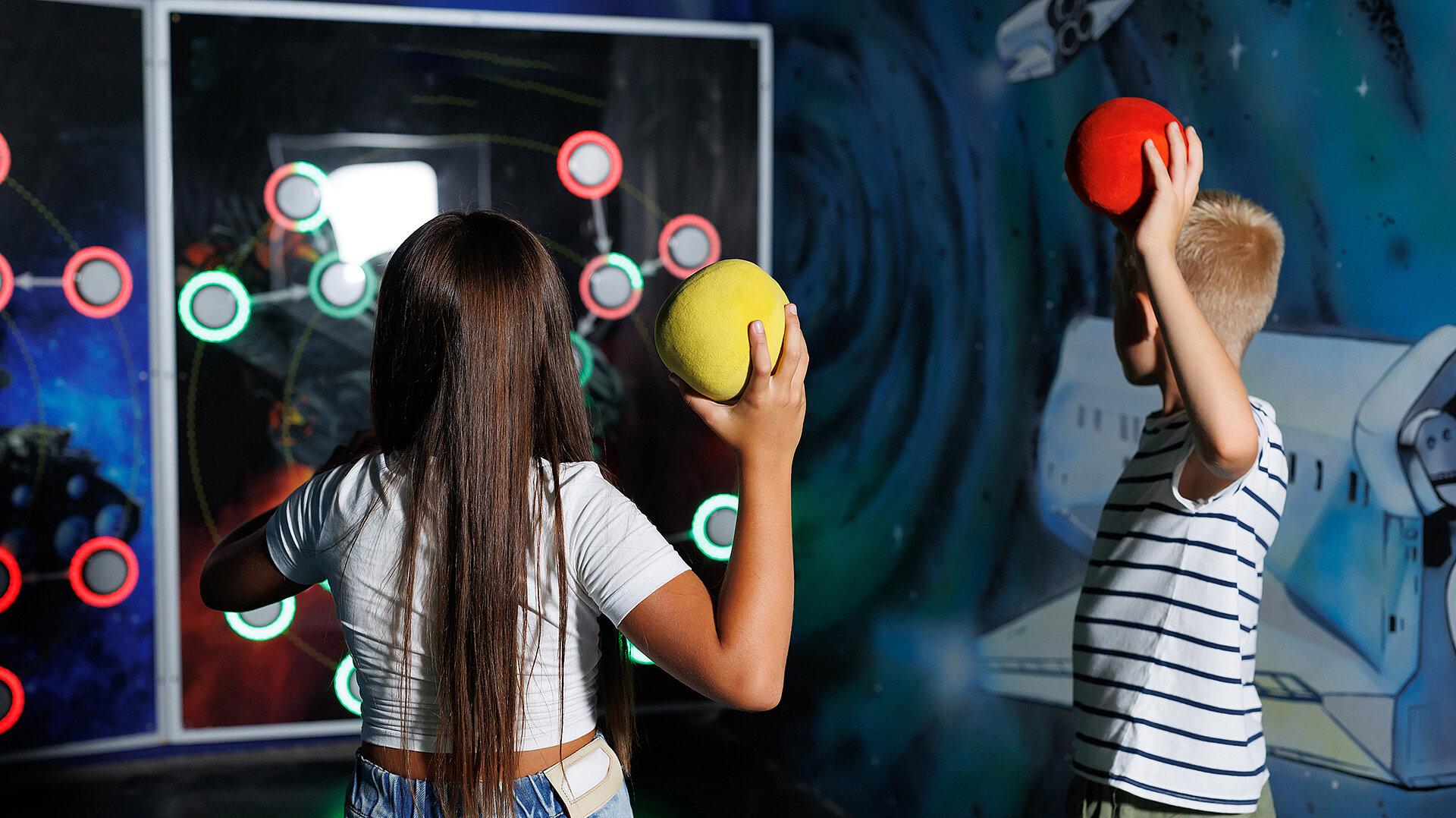 Kinder spielen ein digitales Reaktions- und Wurfspiel in einer interaktiven Spielumgebung – symbolisch für das Motto „Spielen verbindet – auch digital!“ beim Weltspieltag 2026. Jetzt mitmachen und Projekte anmelden.