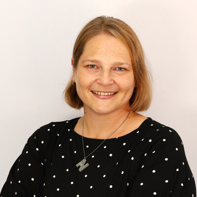 Portät von Nina Eberlein, lächelnd vor hellem Hintergrund