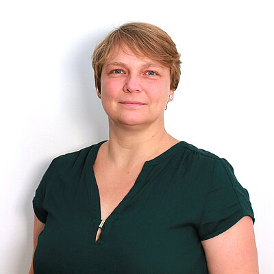 Portät von Claudia Schmidt, lächelnd vor hellem Hintergrund