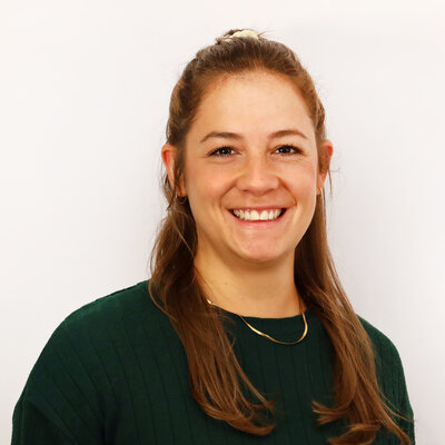 Portät von Dominique Delnef, lächelnd vor hellem Hintergrund