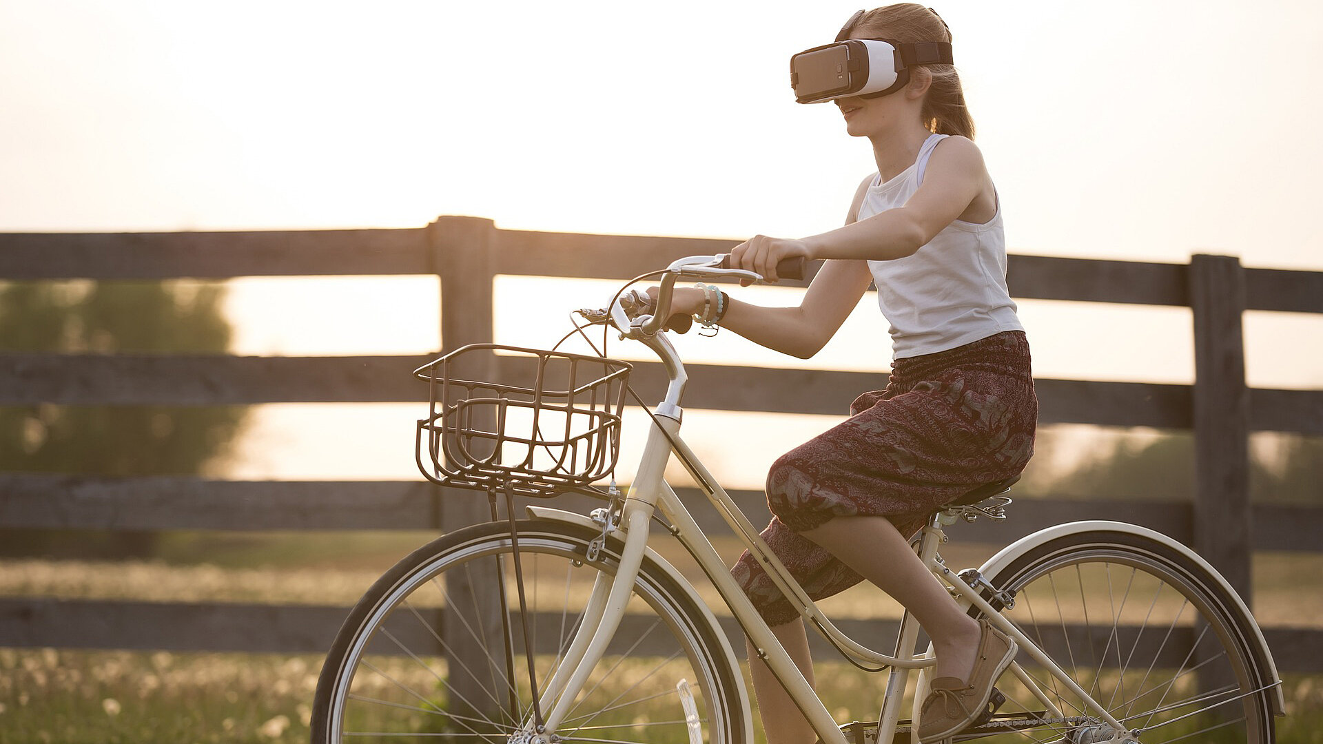 Young woman cycling in nature with VR glasses