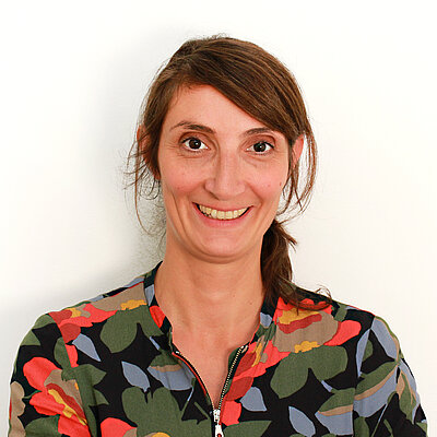 Portät von Natalie Gips, lächelnd vor hellem Hintergrund