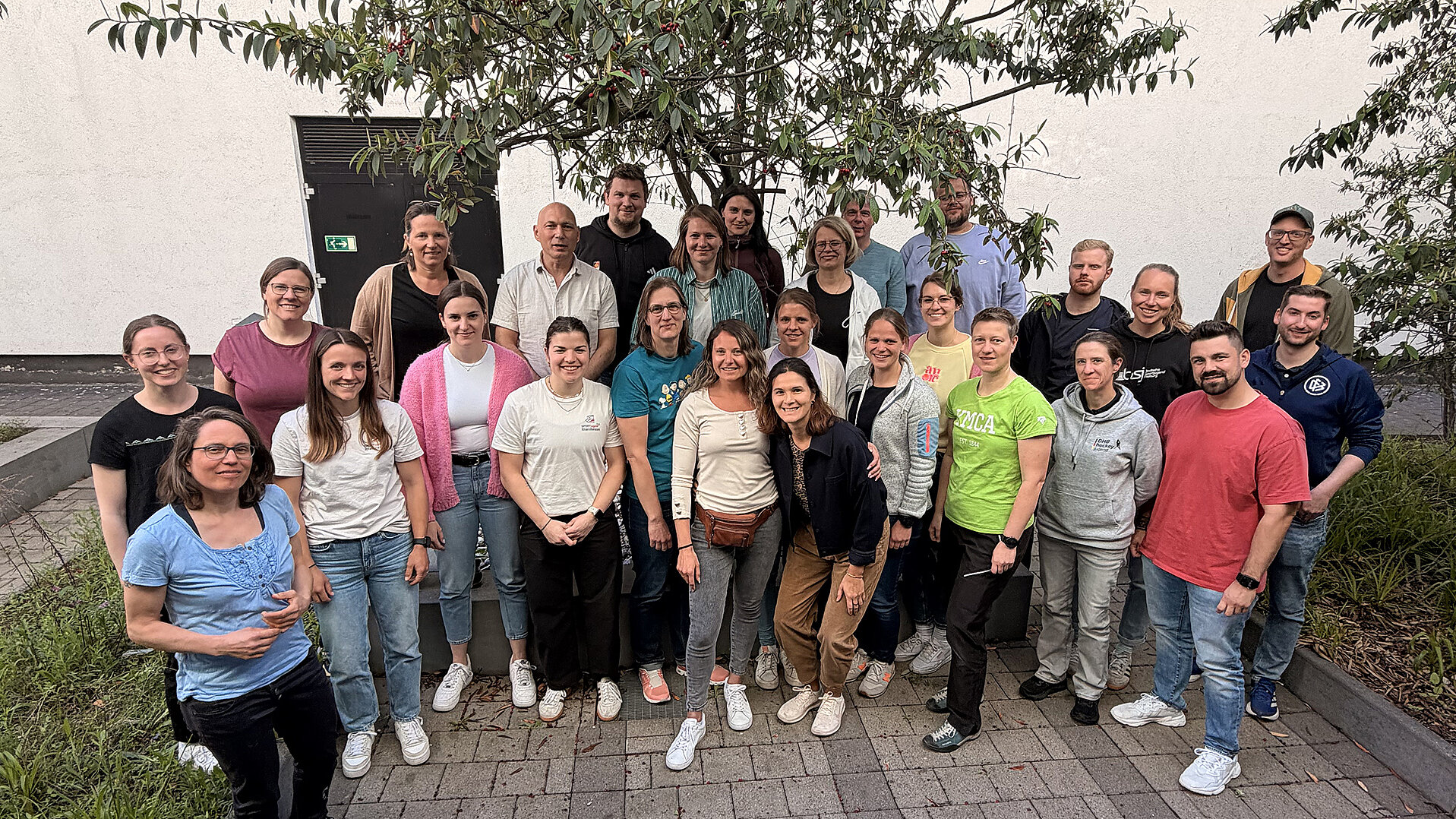 Teilnehmende der dsj- und DOSB-Tagung „Zukunft des Jugendsports in der DOSB-Ausbildungsreform neu denken“ stehen für ein Gruppenfoto im Außenbereich.