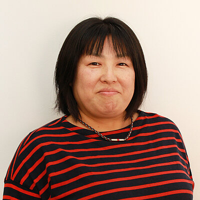 Portät von Michiko Masuch-Furukawa, lächelnd vor hellem Hintergrund