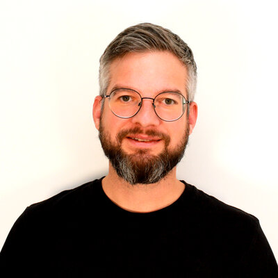 Portät von Alexander Strohmayer, lächelnd vor hellem Hintergrund