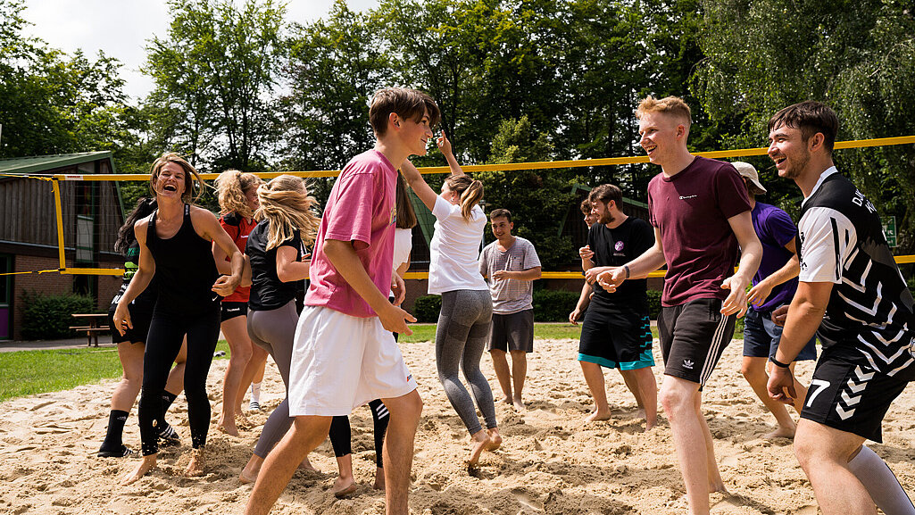 eine Gruppe Jugendliche spielt Beach-Volleyball
