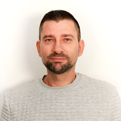 Portät von Thomas Kroll, lächelnd vor hellem Hintergrund