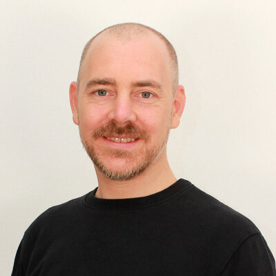 Portät von David Knöß, lächelnd vor hellem Hintergrund