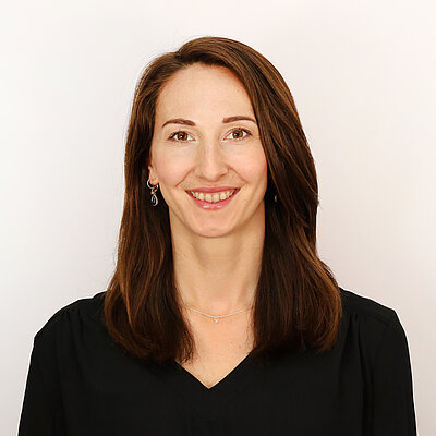 Portät von Dr. Nina Eisenburger, lächelnd vor hellem Hintergrund