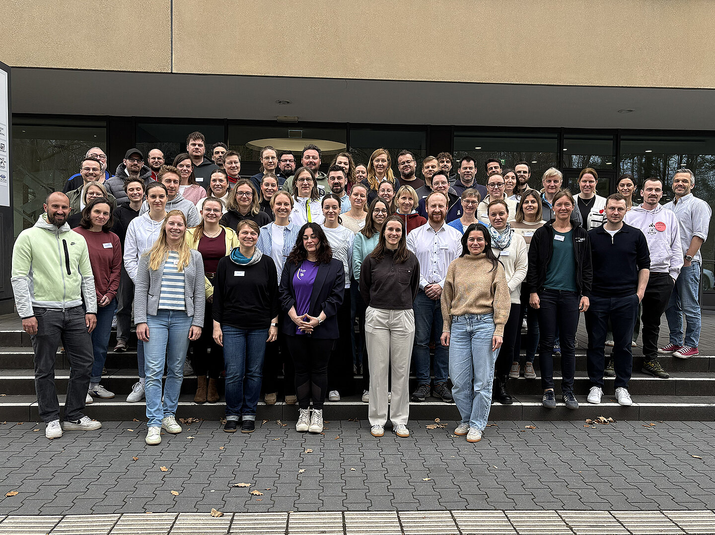 Gruppenfoto der Teilnehmenden beim Auftakt des Projekts NextLevelWir vor einem Gebäude, die gemeinsam auf den Stufen stehen.