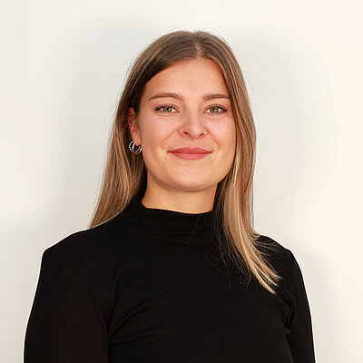 Portät von Aline Kirchgässner, lächelnd vor hellem Hintergrund