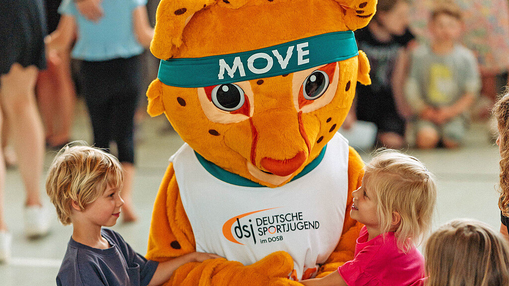 Movelino, Maskottchen der MOVE-Kampagne, spielt mit kleinen Kindern