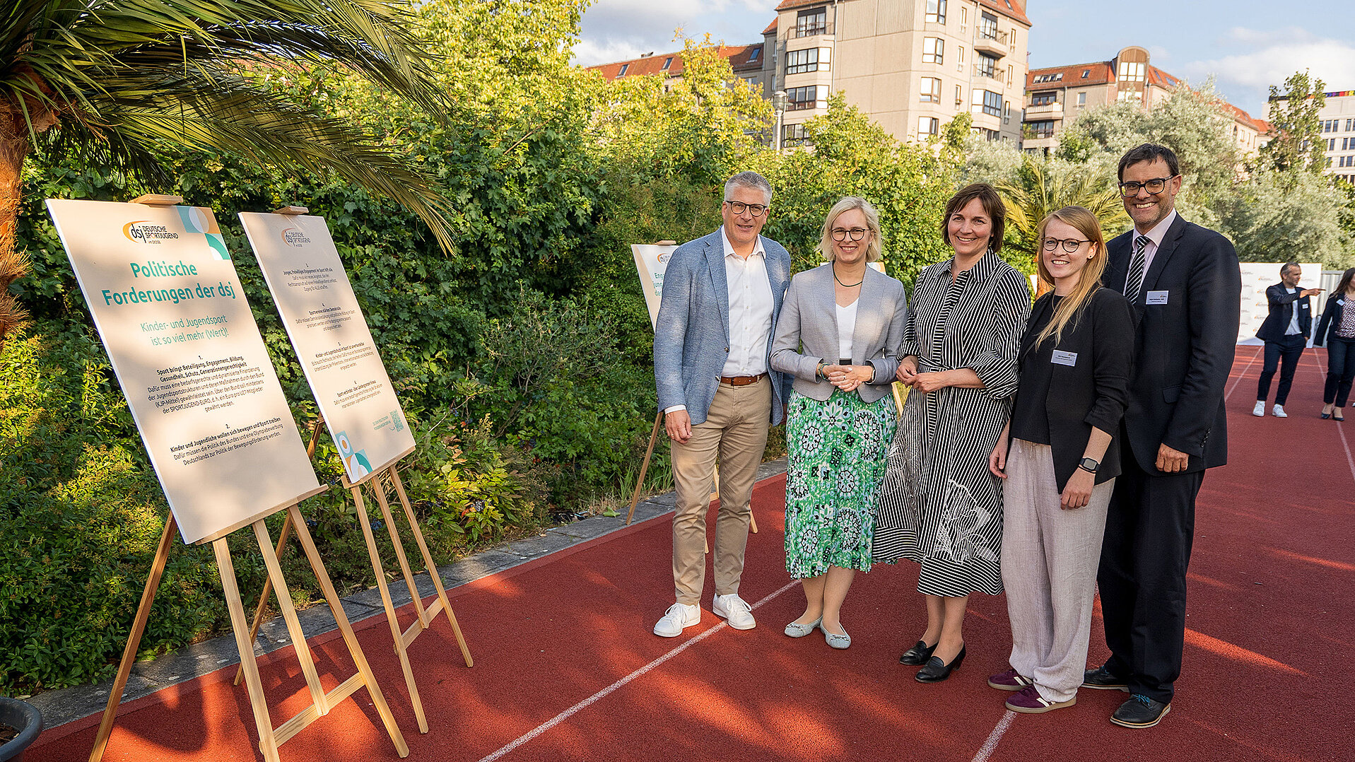 Fünf Personen stehen auf einer roten Laufbahn neben Stellwänden mit politischen Forderungen der Deutschen Sportjugend bei einem politischen Abend zum Kinder- und Jugendsport in Berlin